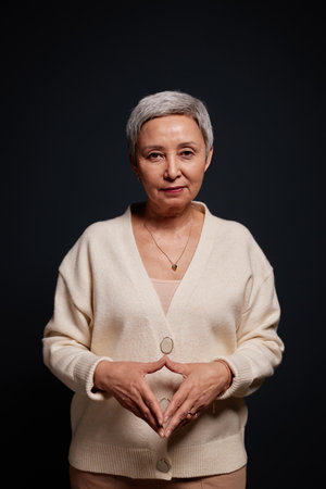 Vertical portrait of modern senior woman with short hair looking at camera on black backgroundの写真素材