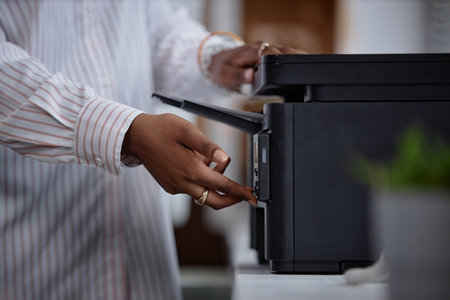 Side view close up on printer and female hands of office worker pressing button on multifunction...