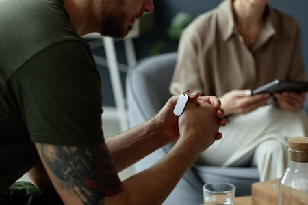 Close up of unrecognizable army veteran holding dog tags necklace in clasped hands during emotional therapy session dealing with grief and PTSD copy spaceの写真素材