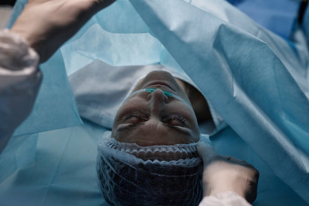 Top view at woman lying on operating table preparing for surgery with assistant holding drape copy spaceの写真素材