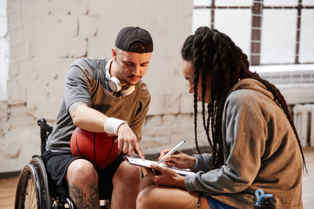 Portrait of young sportsman with disability signing up for game in indoor basketball courtの写真素材