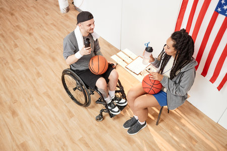 High angle view at basketball player with disability using wheelchair talking break and talking to...
