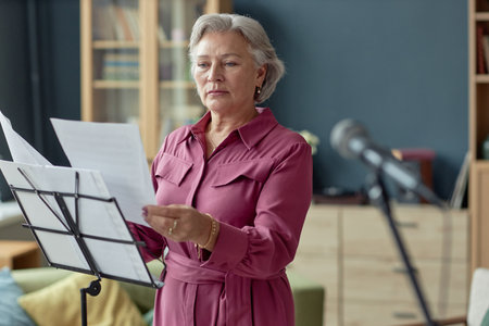 Waist up portrait of elegant senior woman reading sheet music during performance in retirement home copy spaceの写真素材