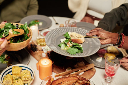 Vibrant close up of festive dinner table with unrecognizable people enjoying meal together and...