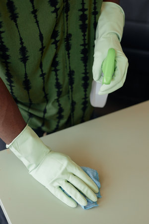 Minimal top view close up of unrecognizable African American man cleaning table and wearing gloves...
