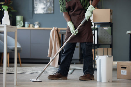 Cropped side view shot of unrecognizable African American man cleaning office and washing floors with mop and bucket, copy spaceの写真素材
