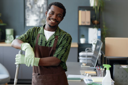 Waist up portrait of young African American man working in cleaning service and wearing uniform...