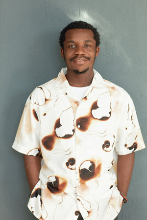MInimal waist up portrait of smiling African American man wearing printed shirt while standing...