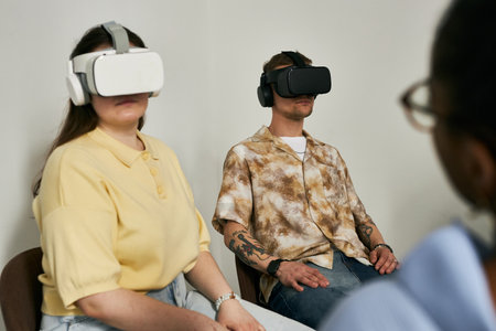 Individuals immersed in virtual reality experiences, wearing VR headsets in minimalist room with plain wall background. Engaging with advanced technology, creating unique virtual experiencesの写真素材