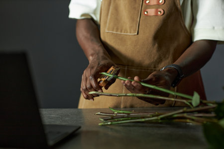 Minimal closeup of male florist arranging bouquet and cutting flower stems in low lighting copy spaceの写真素材