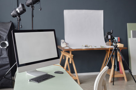Background image of photographers studio with white screen computer on table and product photography...