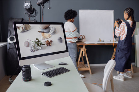 PC computer with product photography pictures on screen at workplace in photo studio two girls...
