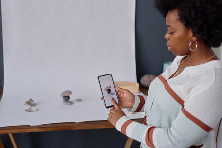 Side view portrait of African American woman using smartphone during professional product...