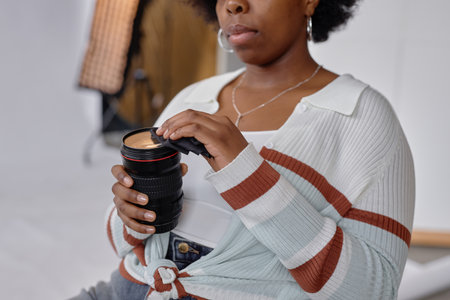Close up of African American woman cleaning photo lenses with wipes while caring for professional equipment in studio, copy spaceの写真素材