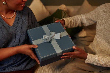 Closeup of African American family exchanging presents on Christmas eve focus on hands holding...