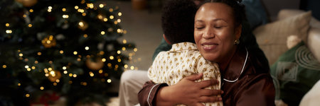 Header Image of happy African American mother embracing son while celebrating Christmas together, copy spaceの写真素材