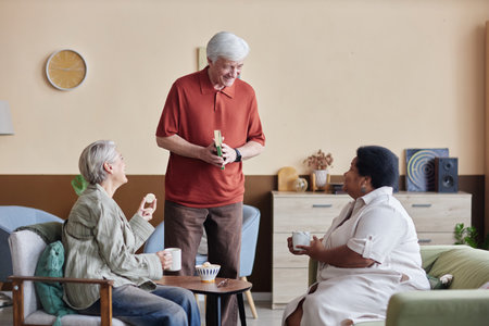 Cozy scene with group of senior people enjoying quiet day indoors together and chatting with smilesの写真素材