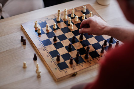 Top view close up of unrecognizable man playing chess with focus on hand moving pawn piece copy...