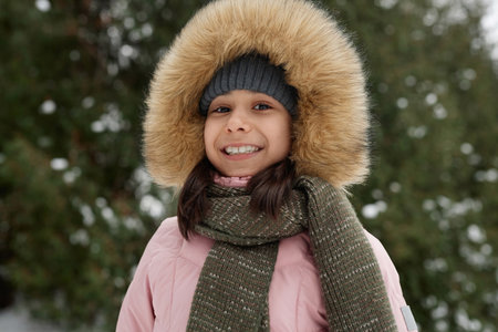 Portrait of smiling young girl wearing pink winter jacket outdoors and looking at camera