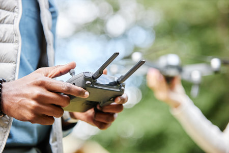 Close up of male hands holding drone controller and pushing buttons while enjoying tech assisted...