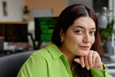 Close up portrait of young female Middle Eastern programmer sitting in office in front of computer...