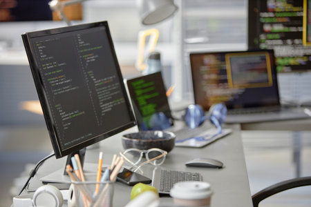 Background shot of software engineer working desk with multiple computer screens displaying...