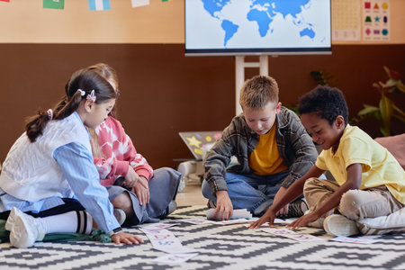 Full length shot of diverse group of kids learning English sitting on floor in school classroom and playing letter matching game togetherの写真素材
