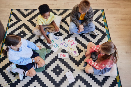 Top view of children playing alphabet game together while sitting on floor in school classroomの写真素材
