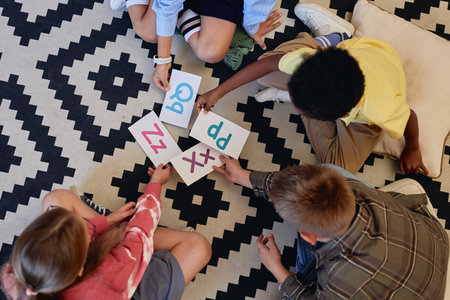 Top down view at group of children laying alphabet cards on floor while playing letter games in primary school classroom and learning English copy spaceの写真素材