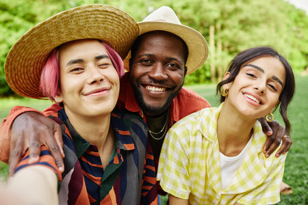 Portrait of three friends enjoying outdoor time smiling warmly at camera posing in park with...