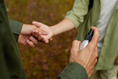 Close-up view of hands using sanitizing spray bottle in outdoor setting for good hygiene practices and cleanlinessの写真素材
