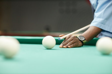 Hand holding billiard cue aiming at cue ball on pool table with other balls spread around creating an engaging game setupの写真素材