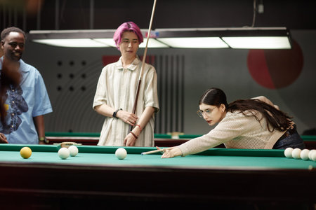 Group of friends enjoying a game of billiards in modern lounge area under ambient indoor lighting...