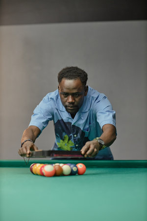 Man aligning billiard balls on table, concentrating on placement Proper focus and skill required for...