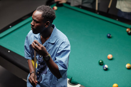 Man focusing on making billiard shot at pool table in relaxed environment holding cue stick and preparing for game playの写真素材