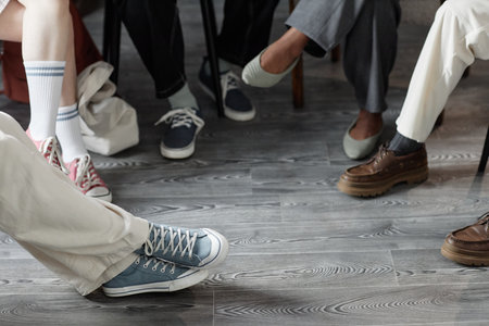Low section shot of group of children sitting on chairs in circle during support group session with...