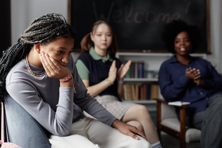 Candid portrait of Black teenage girl crying during therapy session with group of children...