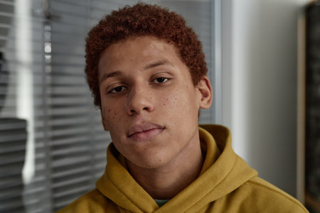 Closeup portrait of multiethnic teenage boy looking at camera with red hair and freckles on dark skin complexion, copy spaceの写真素材