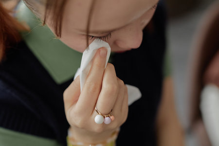 Closeup detail shot of Asian teenage girl crying and wiping tears with tissue while sharing mental...