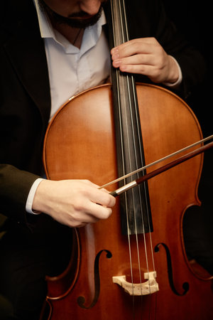 Vertical cropped shot of unrecognizable male classical music artist playing cello with bowの写真素材