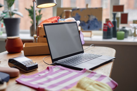 Background shot of laptop with mockup blank screen on cluttered table in cozy thrift store, copy spaceの写真素材