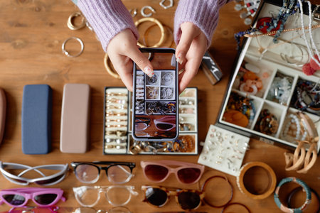 Girl taking photo of flat lay composition with vintage jewelry and fashion accessories, focus on phone screen, copy spaceの写真素材