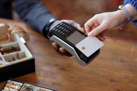 Close up on hand of unrecognizable female customer paying cashless with white mockup credit card and...