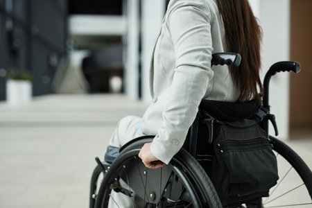 Cropped portrait of young businesswoman in wheelchair entering office building, copy spaceの写真素材