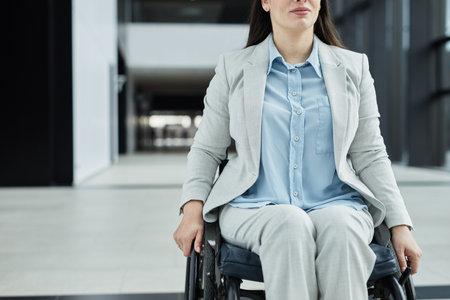 Cropped portrait of young businesswoman in wheelchair entering accessible office building or school, copy spaceの写真素材