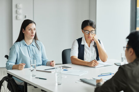 Diverse business team discussing project at table in modern office with focus on young woman in...