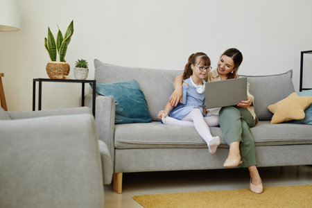 Portrait of young woman using laptop with cute girl with disability, copy spaceの写真素材