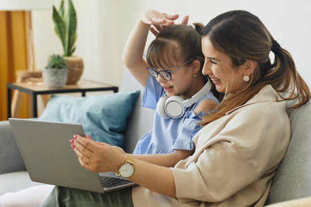 Portrait of cute girl with disability speaking to camera while using video chat with mom, copy spaceの写真素材