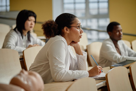Side view portrait of multiethnic young woman listening to lecture in college and taking notes, copy spaceの写真素材