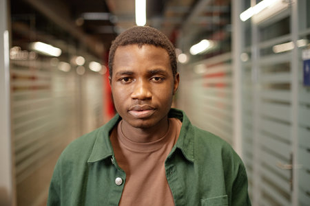 Front view portrait of young African American student looking at camera while standing in college...
